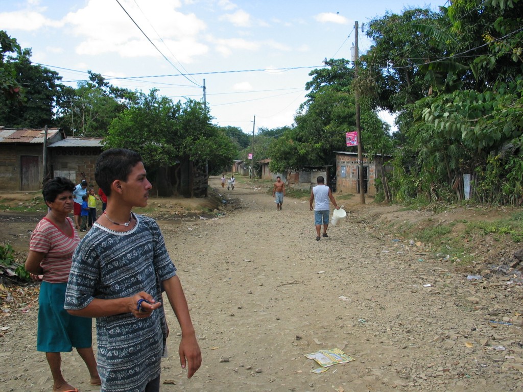 Maria Elena and her son in the street in front of their house. The purple posters are Sandinista advertisement.